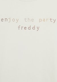 Camiseta de algodón blanca con el texto "disfruta de la fiesta freddy" en piedras metálicas de diferentes colores y tamaños.