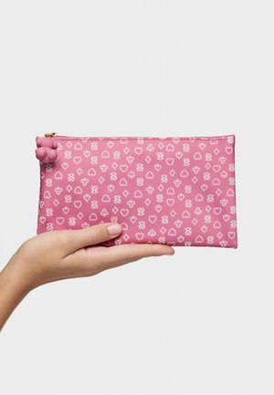 Mano sostiene una funda rectangular rosa con patrón de corazones, diamantes, tréboles y picas blancas, con un pequeño pompón en la cremallera.