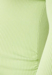 Tecido ribbed verde-claro com textura visível e suaves pregas. O material tem um acabamento liso e um brilho sutil.