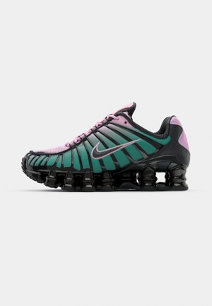 Des chaussures de course Nike Shox en rose et vert avec une tige en mesh et synthétique, un design unique strié et une semelle noire élastique.