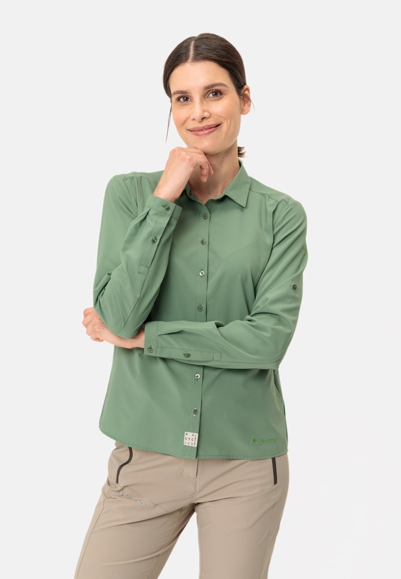 Camicia verde a maniche lunghe con design a bottoni, caratterizzata da un colletto e una leggera lucentezza. Sul lato sinistro è visibile un piccolo logo e dettagli dell'etichetta.