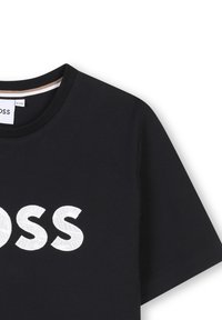 T-shirt in cotone nero con colletto rotondo, maniche corte e scritta bianca ricamata "BOSS" con un motivo testurizzato.