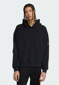 Sort hætte sweatshirt med afslappet pasform, der har manchetter og en kant, lavet af blødt materiale. Indeholder en diskret design detalje på ærmet.