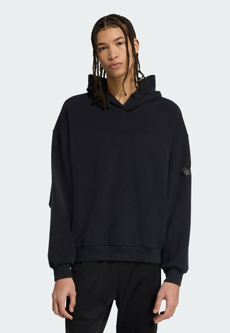 Sort hætte sweatshirt med afslappet pasform, der har manchetter og en kant, lavet af blødt materiale. Indeholder en diskret design detalje på ærmet.