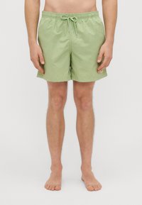 Heledad roheline ujumispüksid kergest kangast. Omavad elastset vööd koos paelaga, külgiseid taskuid ja lihtsat disaini.