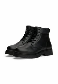 Botas de cuero negras hasta el tobillo con cordones, ojales de metal, collar acolchado y suela de goma gruesa, situadas una al lado de la otra sobre un fondo blanco.