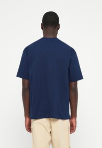 Marineblå bomulds t-shirt med korte ærmer, rund hals og afslappet pasform. Glat tekstur og minimalistisk design, ingen synlige logoer eller mønstre.
