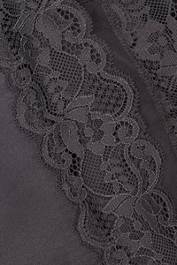 Schwarzer Stoff mit komplexer dunkler Spitze, die Blumenmuster und eine gewellte Kante entlang einer Seite aufweist und so Struktur und Details hinzufügt.