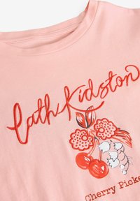 Rožinė medvilninė marškinė su raudonai siuvinėtu užrašu "Cath Kidston" ir gėlių vyšnių dizainu su baltais ir raudonais akcentais.
