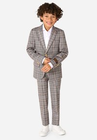 Completo grigio a quadri con rever a punta, chiusura con un bottone e pantaloni coordinati. Tessuto misto cotone con camicia bianca e sneakers bianche.