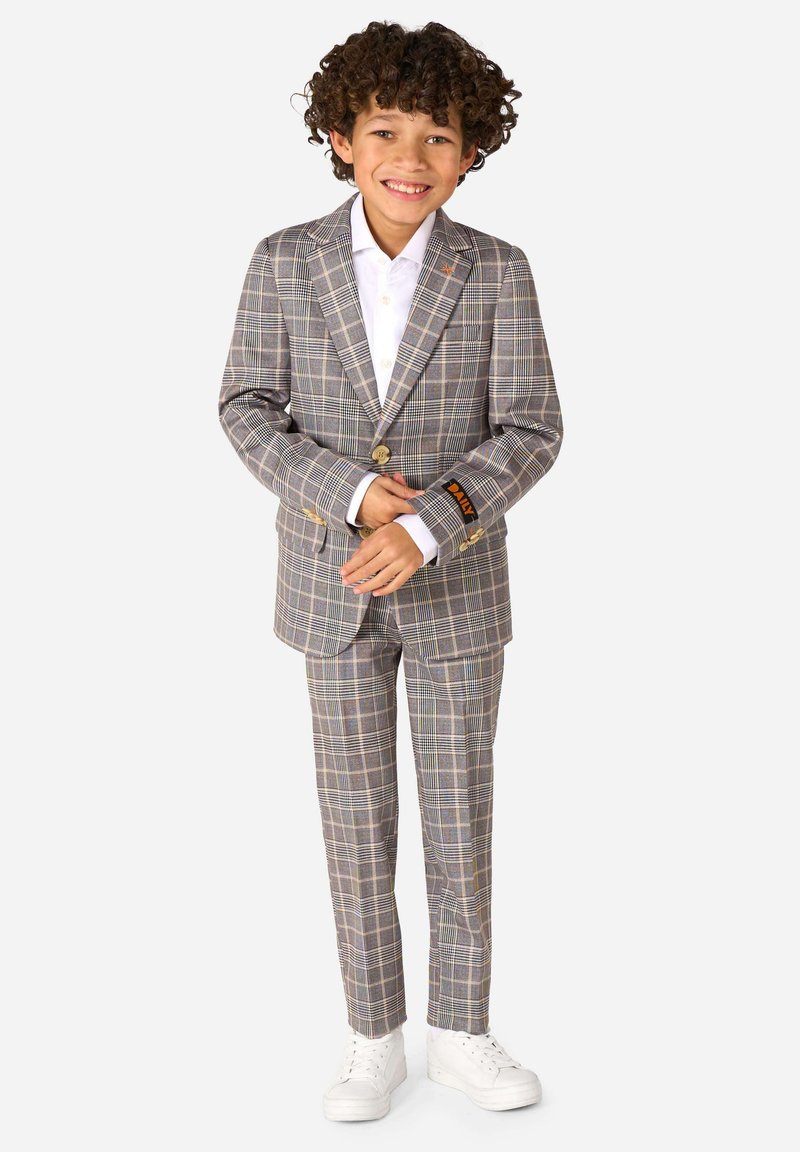 Completo grigio a quadri con rever a punta, chiusura con un bottone e pantaloni coordinati. Tessuto misto cotone con camicia bianca e sneakers bianche.