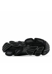 Suela de zapato atlético negro con goma texturizada, que presenta ranuras definidas, patrones circulares y secciones distintas para agarre y flexibilidad.