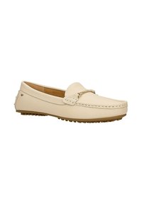 Mocassin en cuir beige avec détail boucle métallique, couture moc toe, et semelle en caoutchouc avec coussinets antidérapants, incliné vers la gauche sur fond blanc.