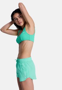 Ensemble athlétique léger vert menthe composé d'un bralette côtelé à fines bretelles et d'un short assorti à cordon de serrage avec poches latérales et détails logo.