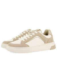 Zapatillas beige y blancas con una combinación de materiales de ante y piel, que presentan cordones blancos y un sutil acento metálico en el lateral.