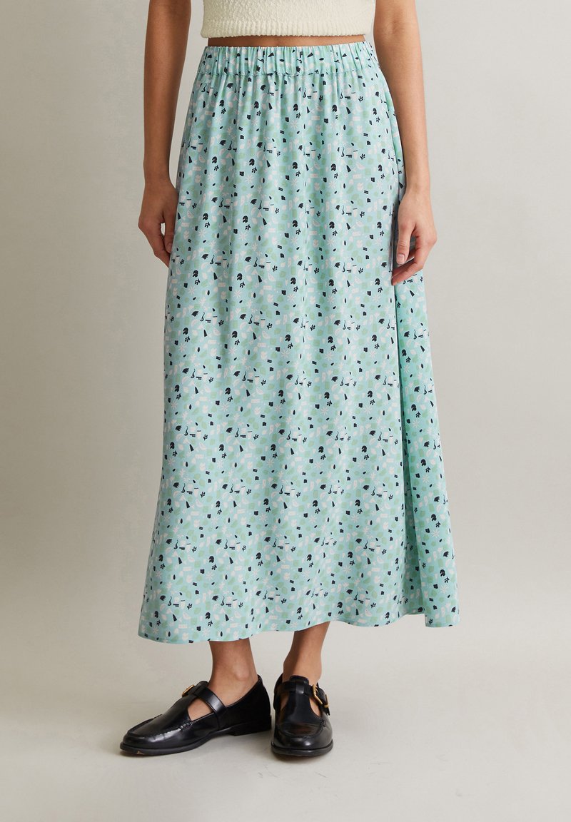 Jupe maxi bleu clair avec un motif floral ; ceinture élastique froncée ; fabriquée en tissu doux ; assortie à des chaussures noires.