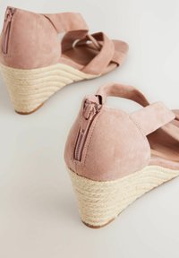 Sandali con zeppa in suede rosa, con suola in juta testurizzata. Presentano una cerniera sul retro e un design a fasce incrociate per una vestibilità sicura e confortevole.