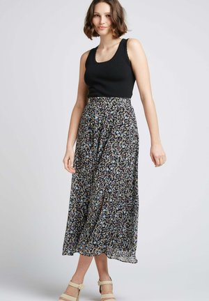 Jupe maxi noire avec des motifs floraux en bleu, jaune et blanc ; matière légère, design fluide, associée à un haut noir ajusté.