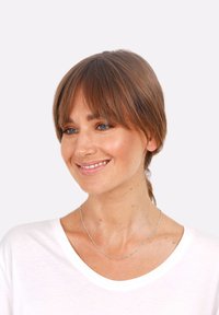 Sølv halskæde med små cylindrisk perler, båret om en bar hals. Model i en hvid bomulds T-shirt med rund halsudskæring og lys brunt hår.