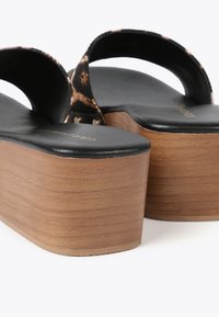 Sandalias de plataforma con una parte superior de textil negro con estampado de leopardo, tacón de bloque de madera y plantilla negra suave con marca dorada.