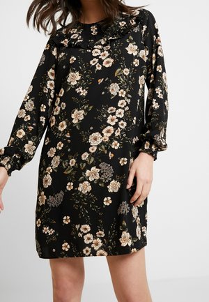 Robe noire à fleurs avec des manches longues, encolure froncée, fleurs beige et crème, feuilles vertes et poignets élastiques. Texture de tissu lisse.