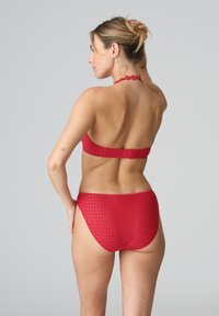 Bikini rojo con una tela texturizada. La parte superior presenta un diseño de cuello halter y la parte inferior ofrece una forma de cobertura media.