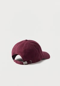 Tumepruun puuvillane pesapallimüts kõverdatud visoori, reguleeritava tagumise rihma ja tekstuurse pinnaga. Lihtne, ilma mustrite või logodeta.