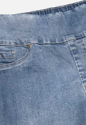 Close-up van lichtblauwe spijkerstof met zicht op de tailleband, voorzak, stiksel en metalen nagelkopdetail op een spijkerbroek.