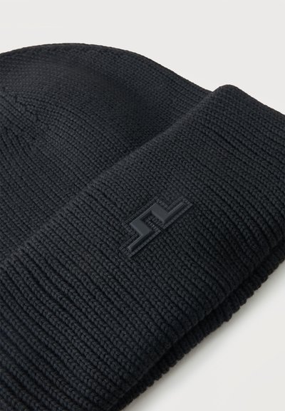 Bonnet en maille noire avec revers plié et petit logo rectangulaire noir sur le revers, présenté sur fond blanc.
