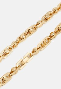 Bracciale in metallo dorato con maglie intrecciate, caratterizzato da accenti arrotondati e un dettaglio centrale inciso con "MK". Finitura liscia e lucida.