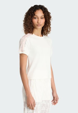 Kurzärmeliges weißes T-Shirt mit kurzem Schnitt, das rosa gestreifte Akzente auf den Schultern und einen weichen, strukturierten Stoff aufweist.