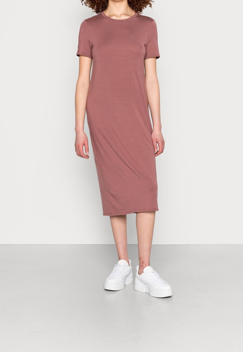 Robe midi mauve à manches courtes, faite d'un tissu doux, avec un col rond et une coupe droite, portée avec des sneakers blanches à semelle épaisse.