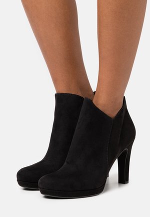 Black suede ankle boots with a sleek design, featuring a v-cut opening, rounded toe, and a high stiletto heel. Smooth texture.