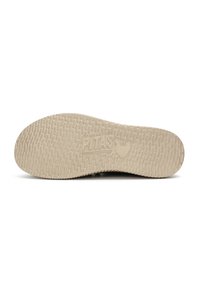 Suela de zapato de goma beige con una superficie texturizada, presentando un logo de pollo y "PITAS" grabado en el centro.