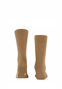 Chaussettes montantes de couleur marron clair uni, avec un haut côtelé et une texture lisse. Pas de motifs visibles ni de détails supplémentaires.