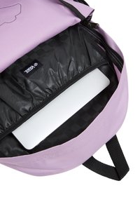 Interno di uno zaino viola con fodera nera, dotato di uno scomparto imbottito per un laptop. Chiusura a zip con dettagli neri e branding.