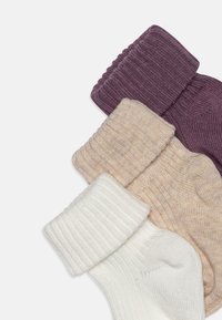 Tre calzini arrotolati di colori diversi: bordeaux, beige e bianco, con texture a coste sui polsini e tessuto liscio sulla parte centrale.