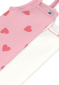 Δύο αμάνικα μπλουζάκια: ένα ροζ με μοτίβα κόκκινων καρδιών και ένα απλό λευκό, το καθένα με λεπτές τιράντες και ραμμένα περιθώρια.