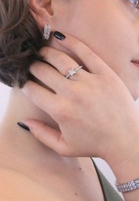 Set di gioielli in argento, composto da orecchini a bottone, un anello con design a stella decorato con pietre trasparenti e un bracciale texturizzato.