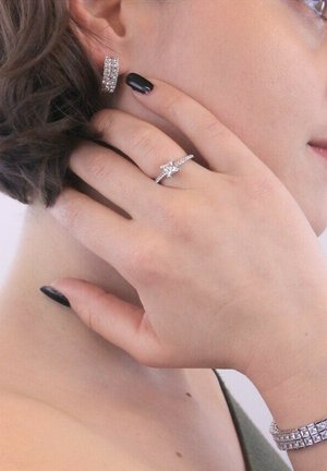 Silbernes Schmuckset, bestehend aus Ohrsteckern, einem Ring mit einem Sterndesign und klaren Steinen sowie einem strukturierten Armband.