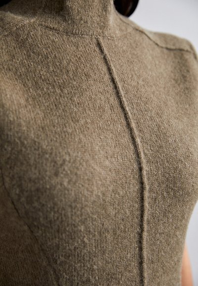 Beiger Wollpullover mit hohem Kragen und vertikalen Nahtdetails, mit strukturiertem Finish und enger Passform am Körper.