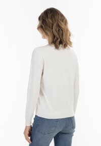 Maglione leggero a girocollo in morbido punto crema. Presenta maniche a costine e orlo, con una vestibilità rilassata e dettagli di cucitura minimi.