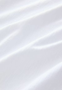 Witte katoenen stof met een glad, licht textuur oppervlak, dat zachte plooien en kreukels vertoont. De stof lijkt lichtgewicht en ademend te zijn.