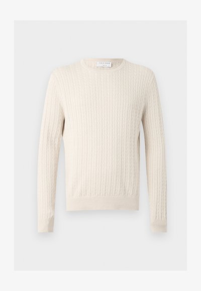Πουλόβερ σε κρεμ απόχρωση με πλεκτό σχέδιο, μακριά μανίκια και στρογγυλή λαιμόκοψη, που εμφανίζεται σε απλό, ανοιχτό φόντο.
