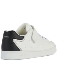 Sneaker bianco con accentuazione nera sul tallone, realizzato in pelle liscia. Presenta fori per la traspirabilità e una fascia in Velcro con lacci.