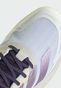 Svijetlopurpurena sportska cipela s teksturiranim mrežastim gornjištem, glatkim naglascima i debelim bež potplatom s ljubičastim vezicama i detaljima.