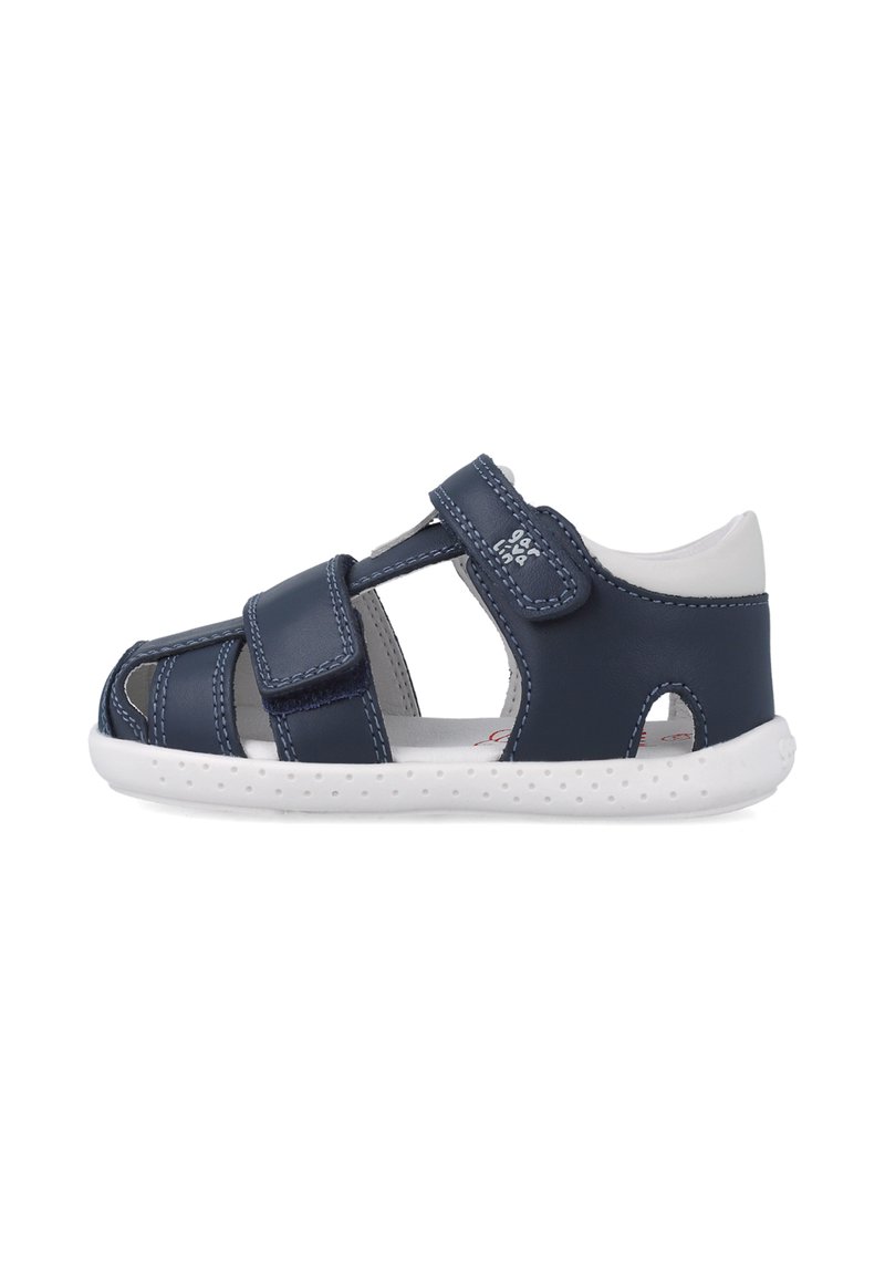 Sandalias sintéticas azul marino con suela blanca, que presentan cierres de correas de gancho y bucle, aberturas para ventilación y detalles de costura en contraste.
