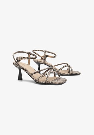 Sandaler med stropper og høje hæle i slangeskinds mønster, i beige og sorte nuancer, med en slank hæl og firkantet tådesign.