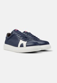 Pair of navy blue low-top sneakers with white side accents, white rubber soles, and red logo on tongue, shown on white background.