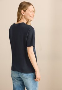 Camiseta de algodón azul marino con un corte relajado, mangas cortas y dobladillo curvado. Presenta una textura sutil y un diseño minimalista en la parte posterior.